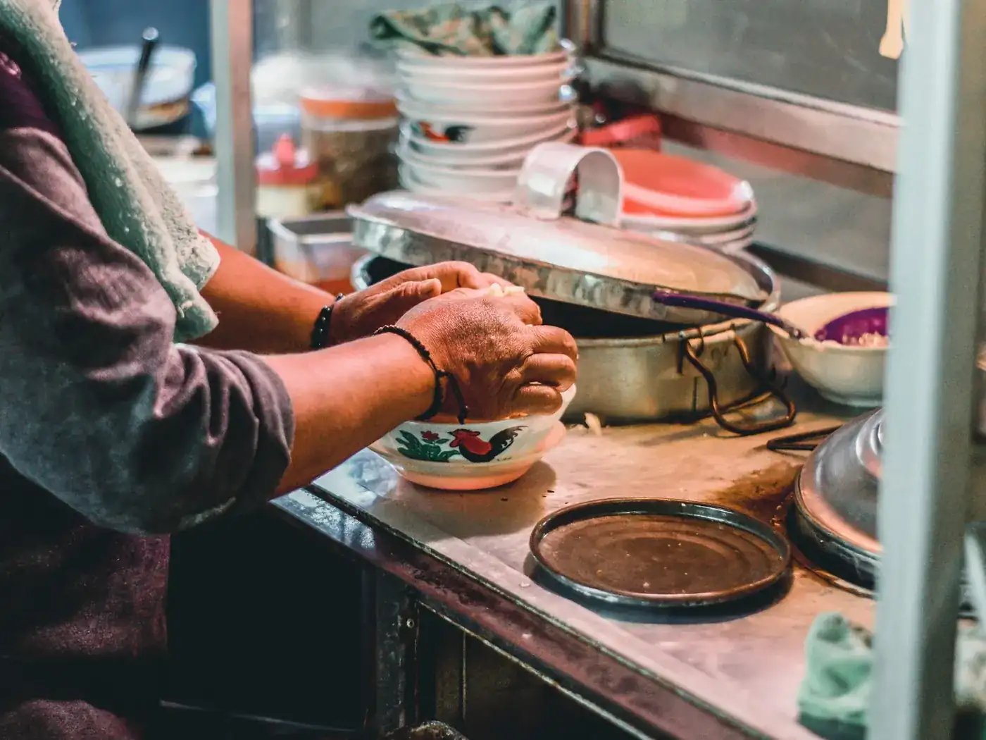 A cook working over pans in a small open kitchen