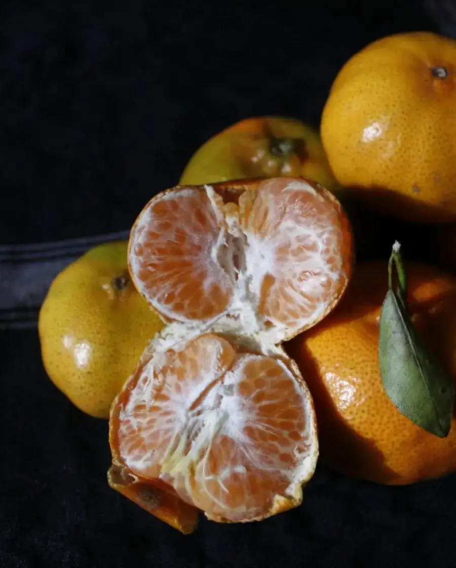 Peeled and whole oranges on a dark background